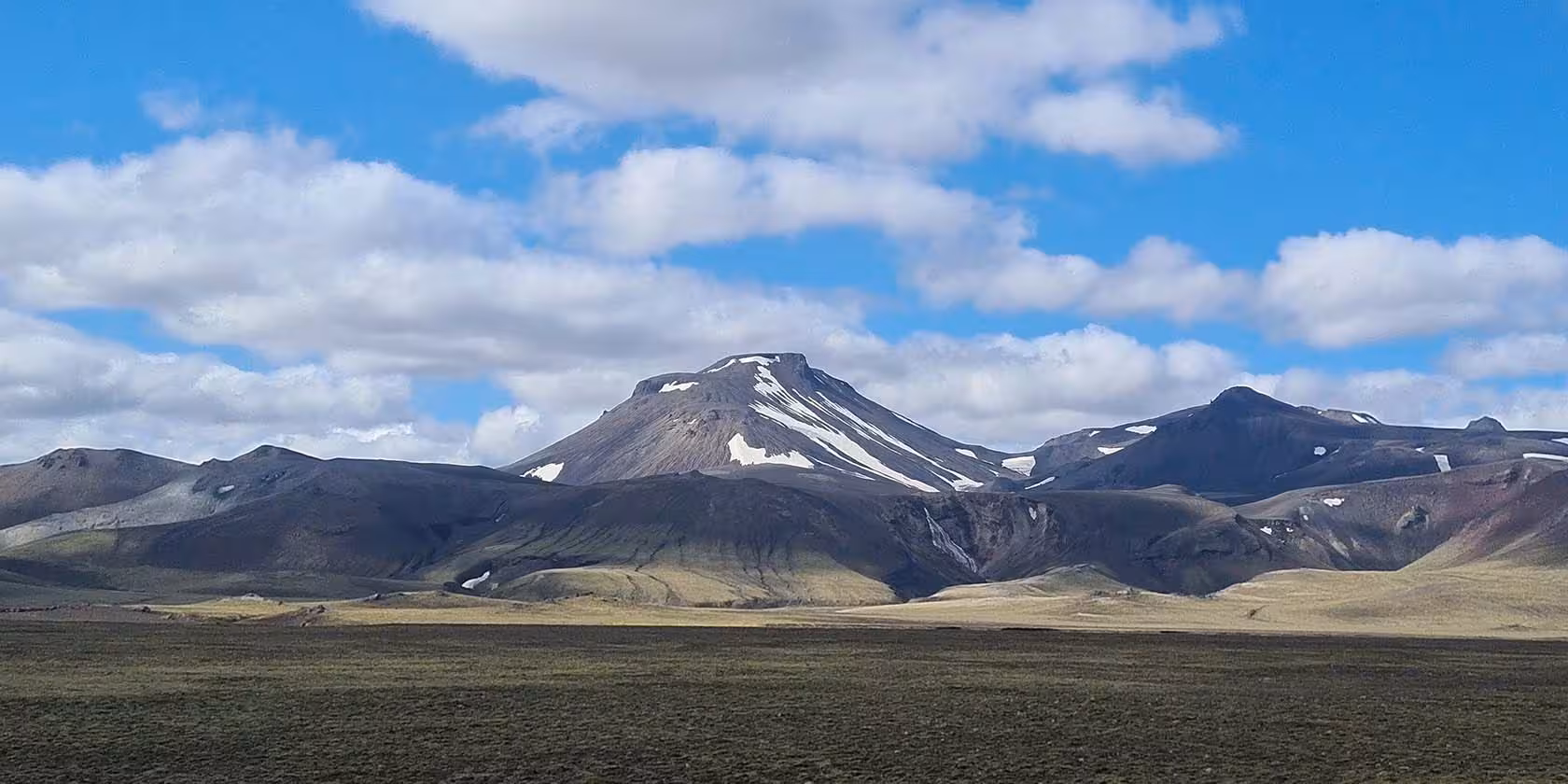 Snow-capped volcanic peak in Fjallabak Nature Reserve Iceland with dark lava highlands and open plain