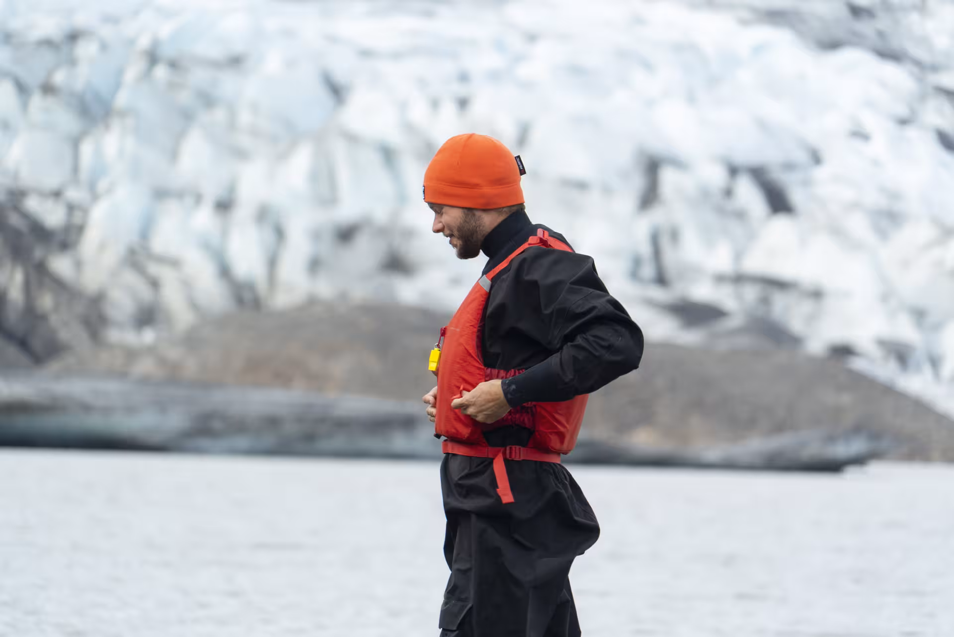 Tour guide in drysuit and life vest by Fláajökull glacier lagoon, gearing up for kayak and glacier hike combo