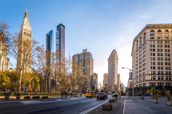 Flatiron Building and Fifth Avenue streetscape with yellow taxis and Madison Square Park trees, New York City