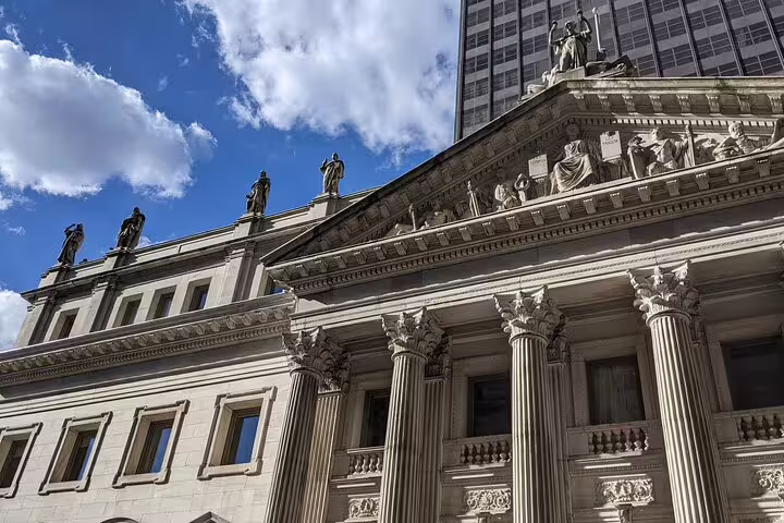 Neoclassical building with columns and statues against blue sky in Flatiron NYC