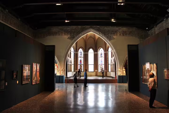 Travelers explore an elegant vaulted gallery with stained glass and Renaissance art on an Accademia Gallery small group tour