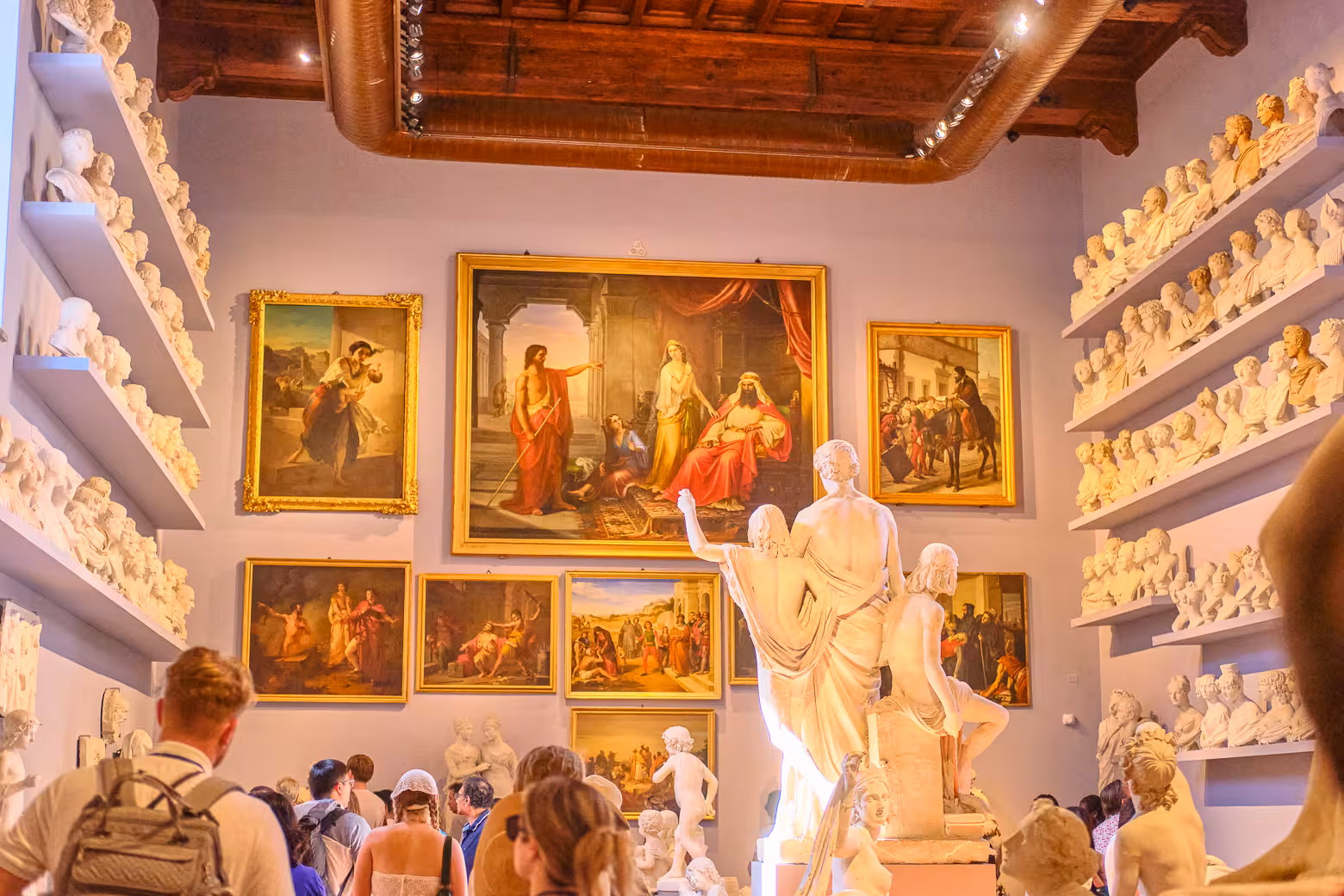 Visitors exploring art and sculptures in the Accademia Gallery during the monolingual small group tour in Florence.