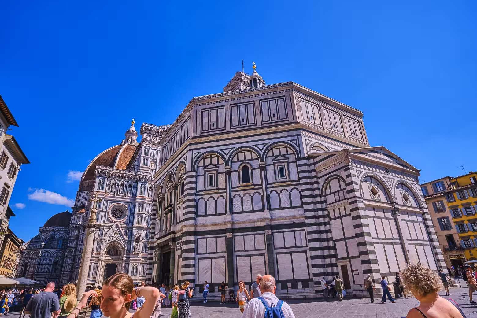Tourists admire Florence Cathedral and Baptistery under clear skies on guided walking tour.
