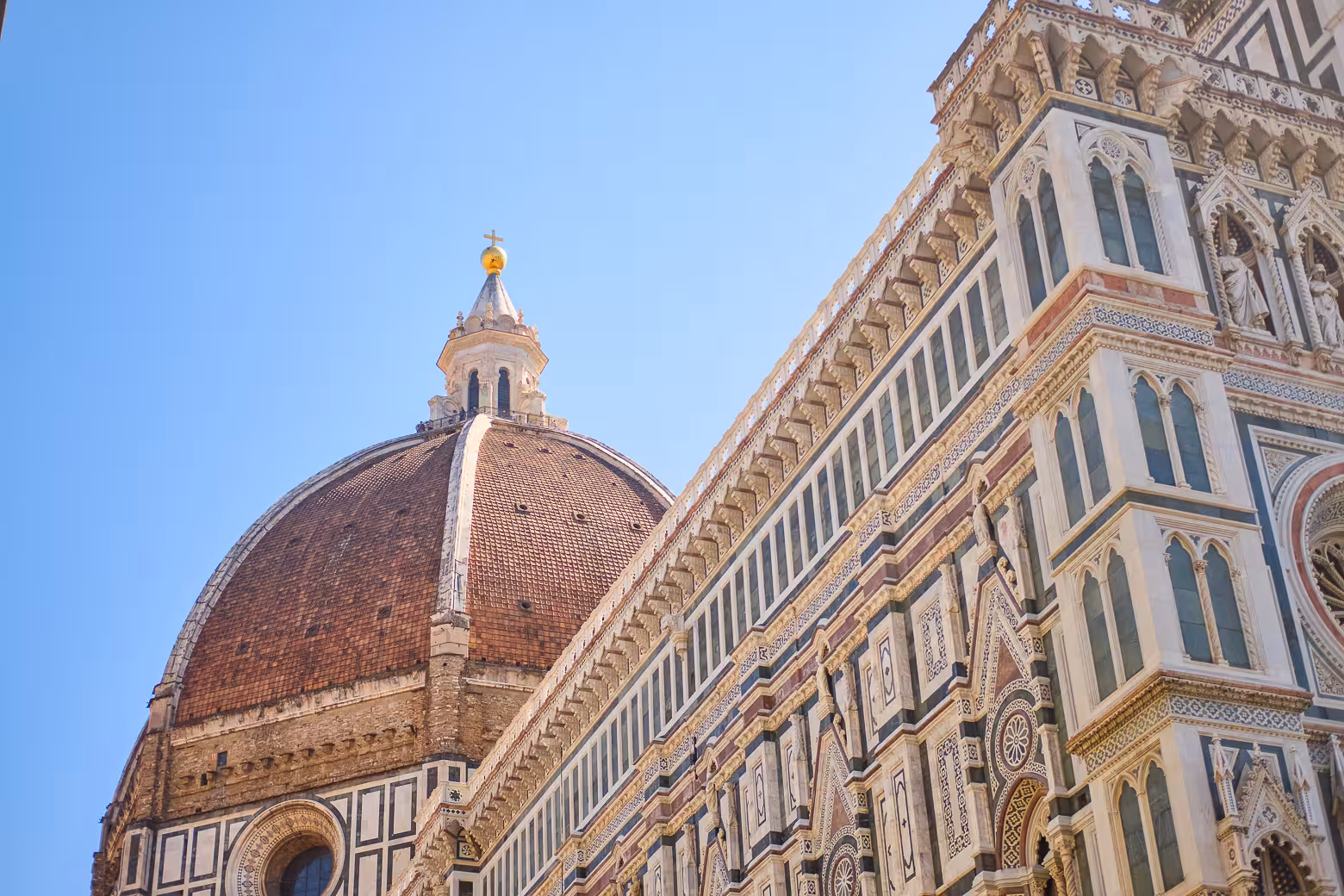 Close-up of Florence Duomo's intricate facade and dome under a clear sky on a small group guided tour.