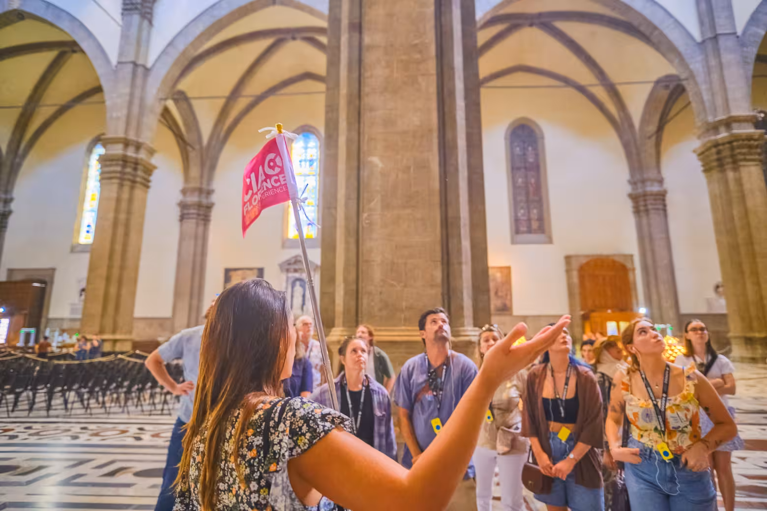 Tour guide leading a small group inside Florence Duomo Cathedral, highlighting architectural details and history.