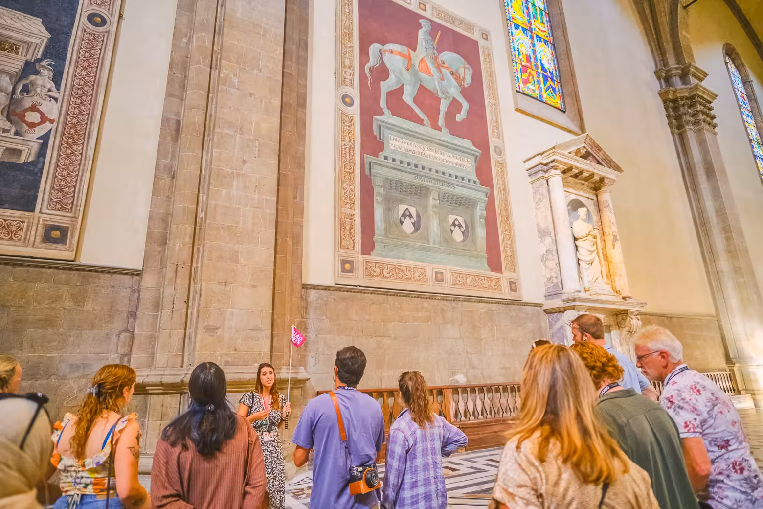 Visitors gather around a guide inside Florence Duomo Cathedral, admiring intricate frescoes and stained glass windows.