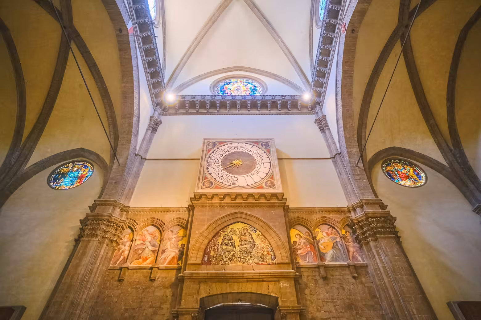 Interior of Florence Duomo Cathedral featuring ornate frescoes and historical clock during a guided tour.