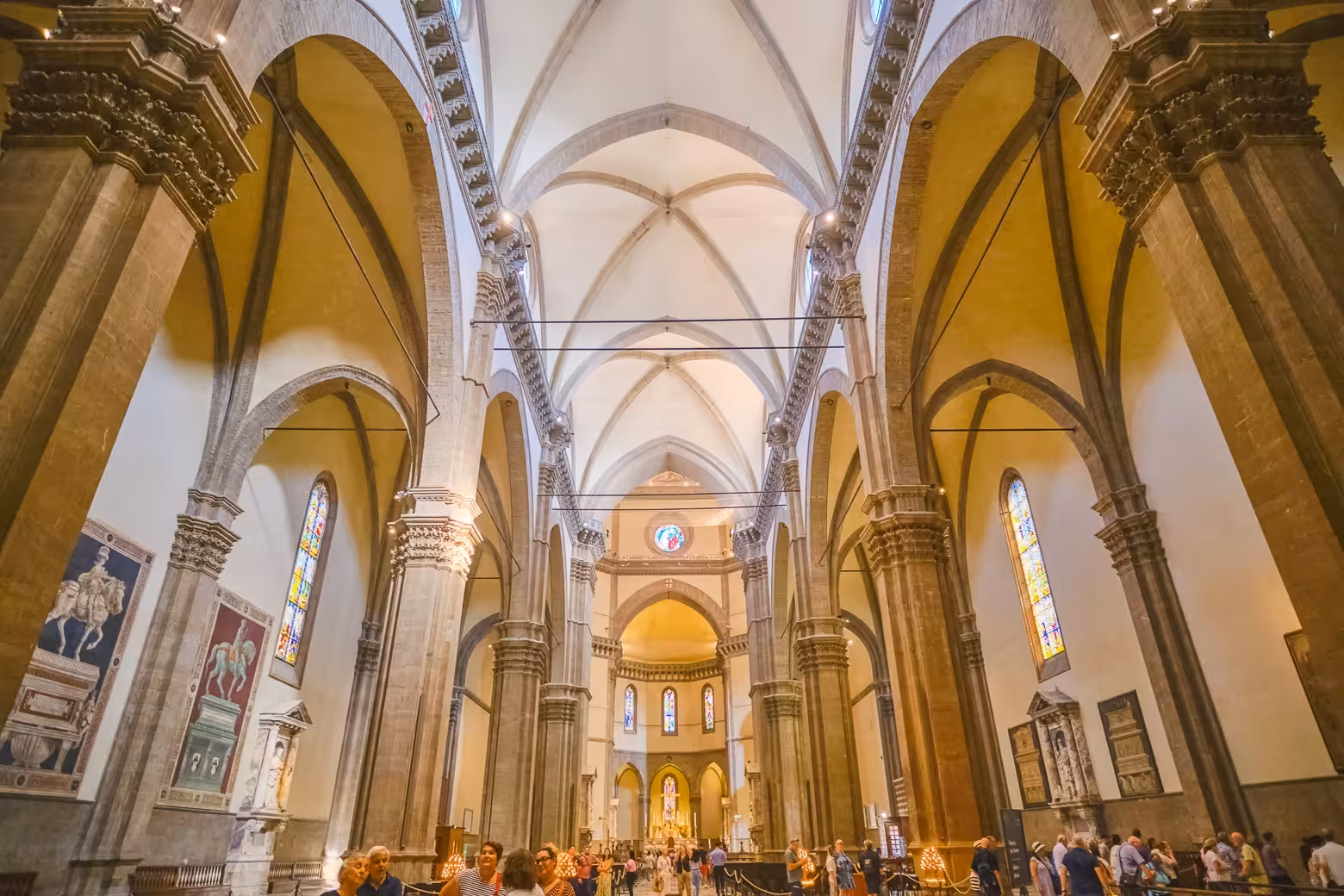 Visitors explore the magnificent interior of Florence Duomo Cathedral, featuring intricate architecture and stained glass windows.