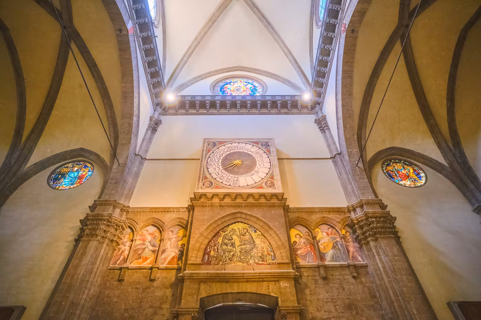 Intricate clock and stained glass at Florence's Duomo, highlighting its Renaissance artistry.