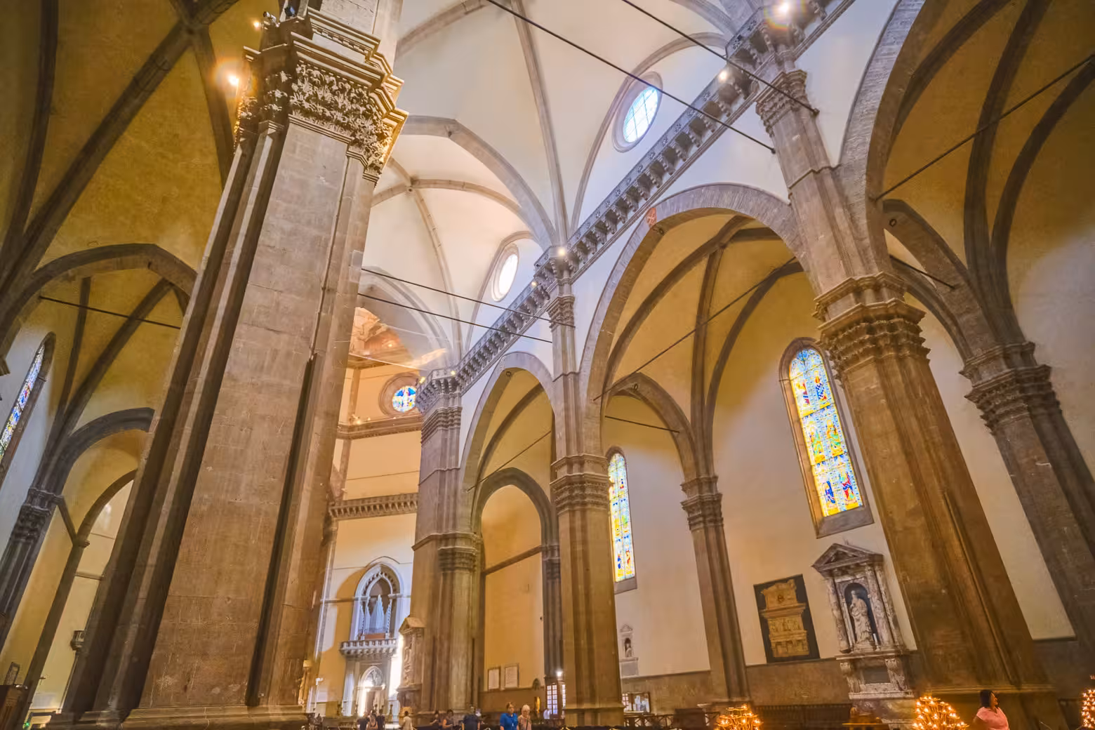 Explore the majestic interiors of Florence's Duomo Complex with stunning arches and vibrant stained glass windows.