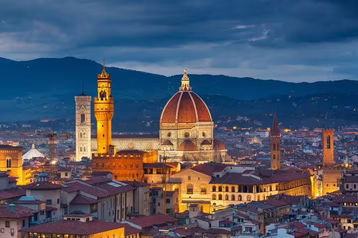 Florence skyline at dusk with illuminated Duomo cathedral dome and Palazzo Vecchio tower