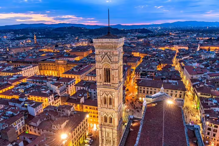 Aerial twilight view of Giotto's Bell Tower and Florence cityscape with glowing streets at dusk