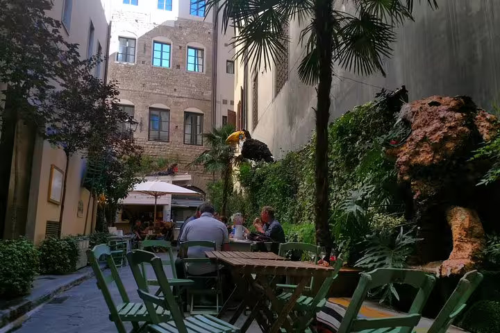 Outdoor courtyard cafe in Florence medieval old town with lush greenery and historic stone buildings