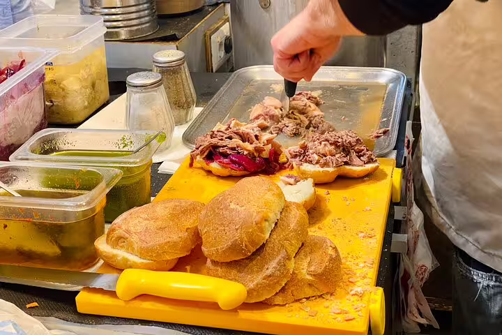 A vendor preparing authentic lampredotto sandwiches with crusty rolls on a cutting board during a Florence food tour