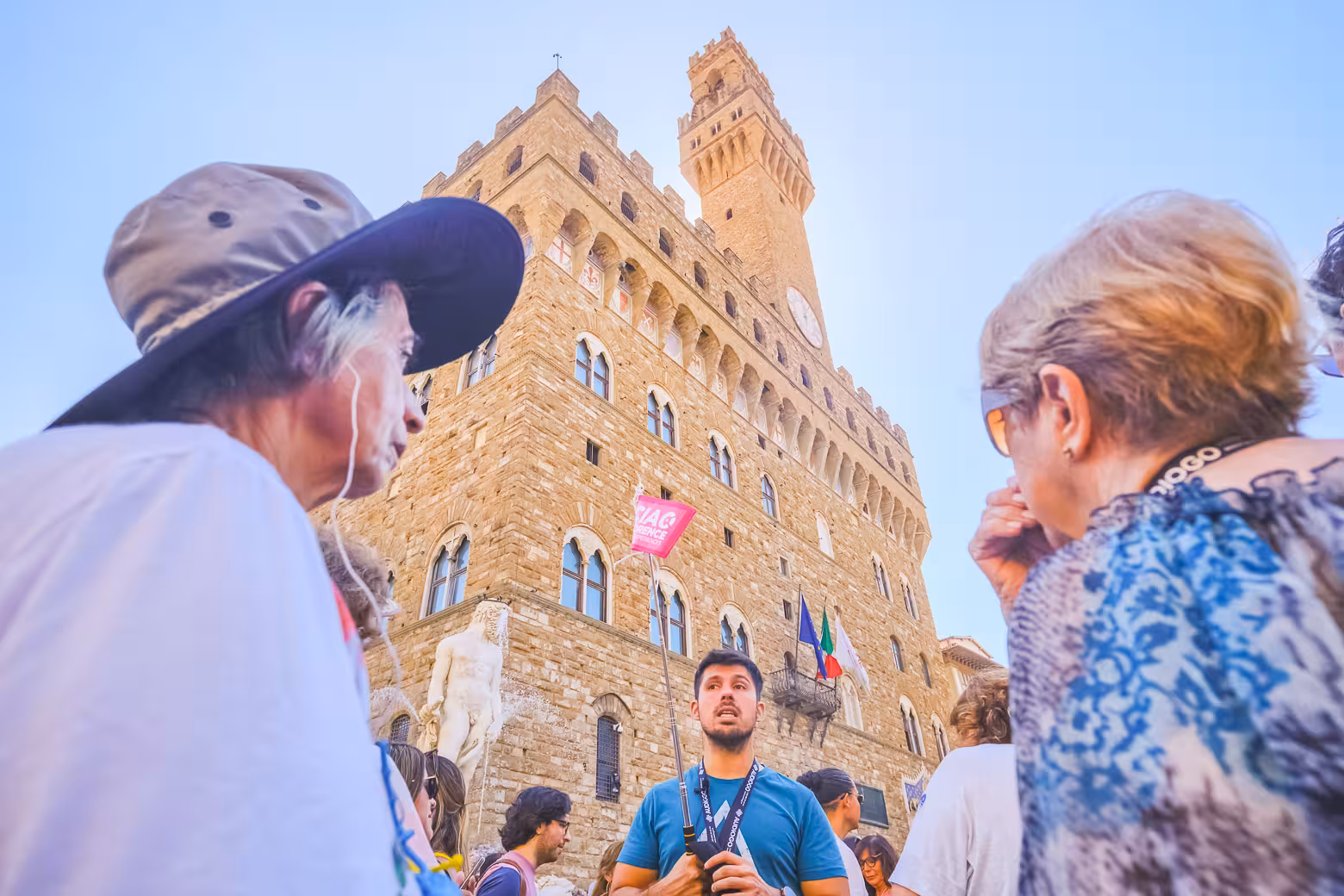 Visitors explore Florence's Palazzo Vecchio on a guided walking tour, admiring its medieval architecture and vibrant atmosphere.