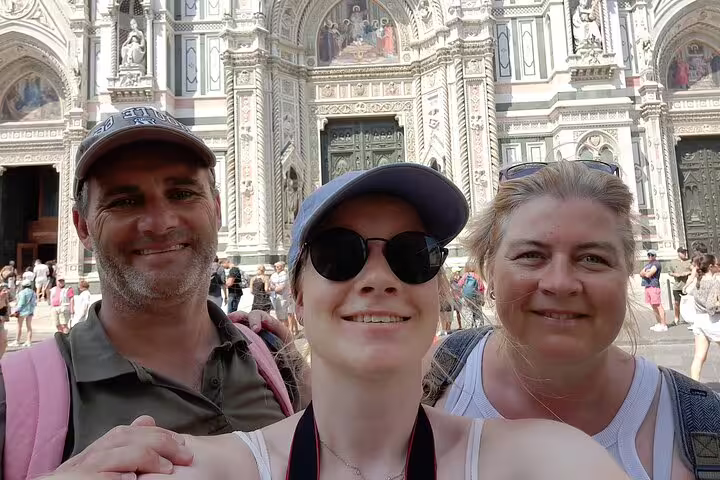 Three tourists smiling in front of Florence Cathedral during a self-guided walking tour