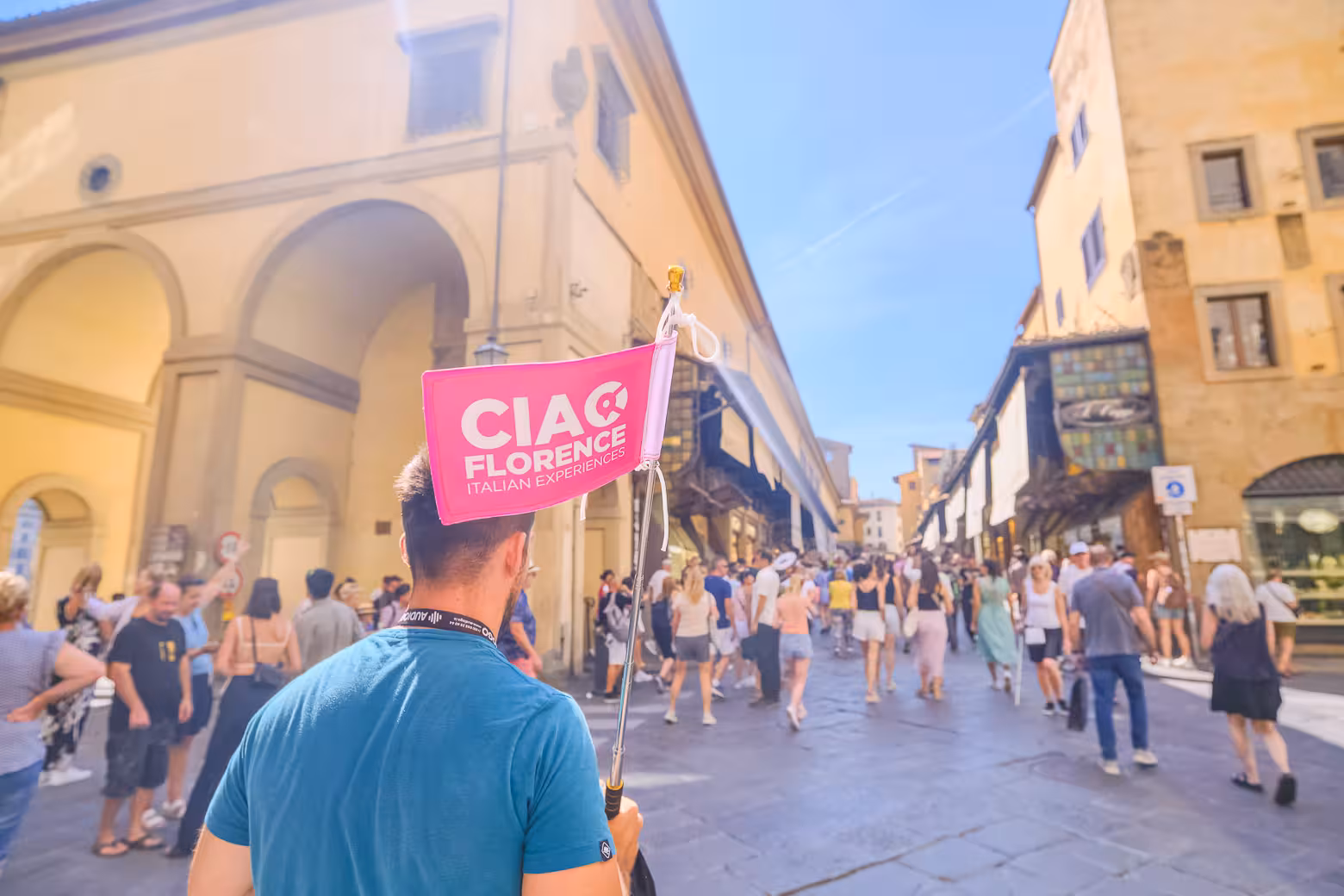 Tour group walks through historic Florence, led by guide with pink flag, during a shore excursion from Livorno.