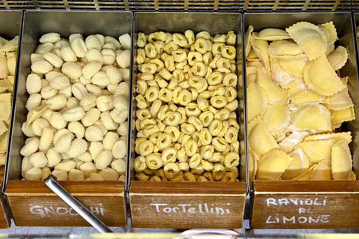 Fresh handmade gnocchi tortellini and lemon ravioli displayed at a traditional Florence street food market stall