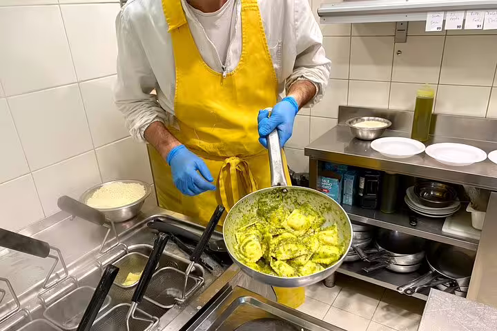 Florence chef in yellow apron cooking fresh pesto tortellini in a pan during a street food sightseeing tour