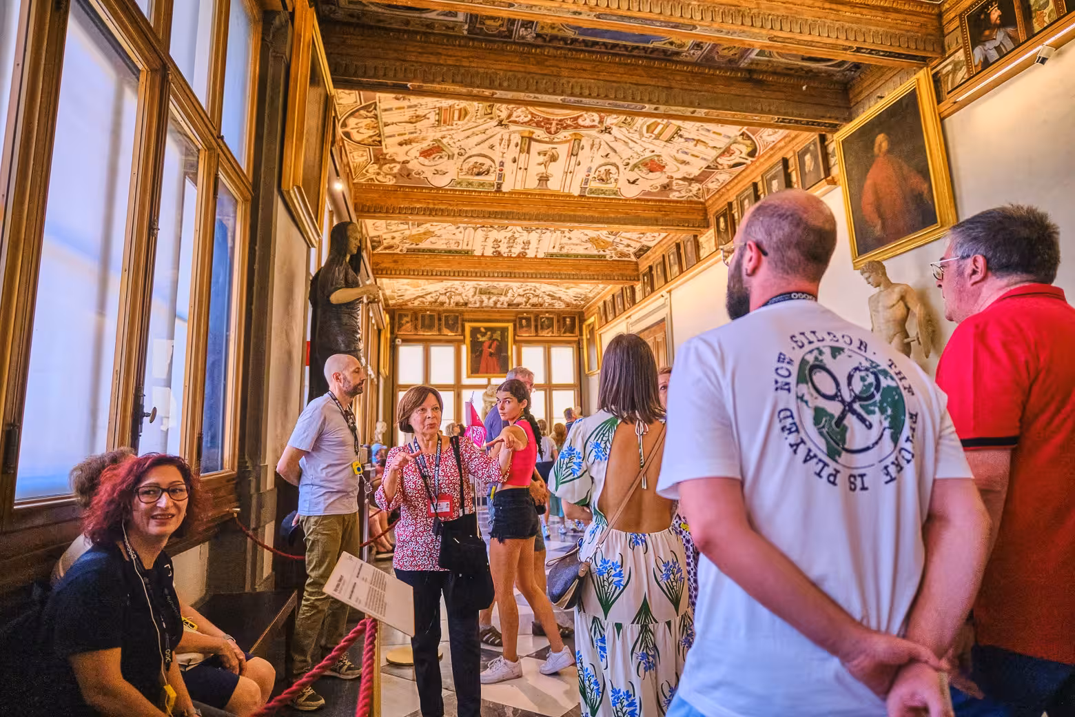 Tourists explore the ornate halls of Florence's Uffizi Gallery, captivated by its art and architecture.