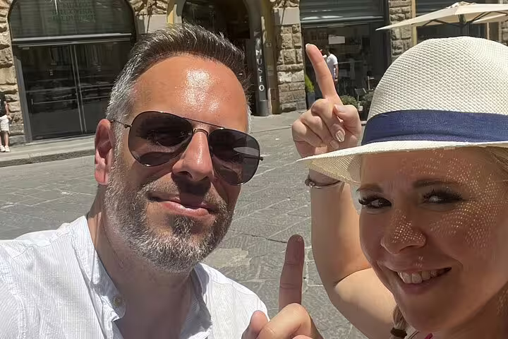 Couple taking selfie in Florence piazza pointing up during Michelangelo self-guided walking quest