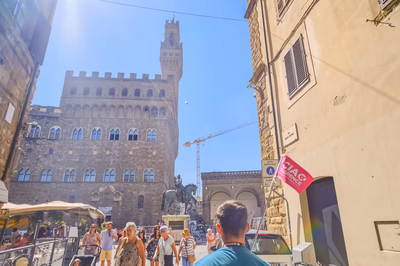 Tourists explore Florence near Palazzo Vecchio and equestrian statue on guided walking tour.