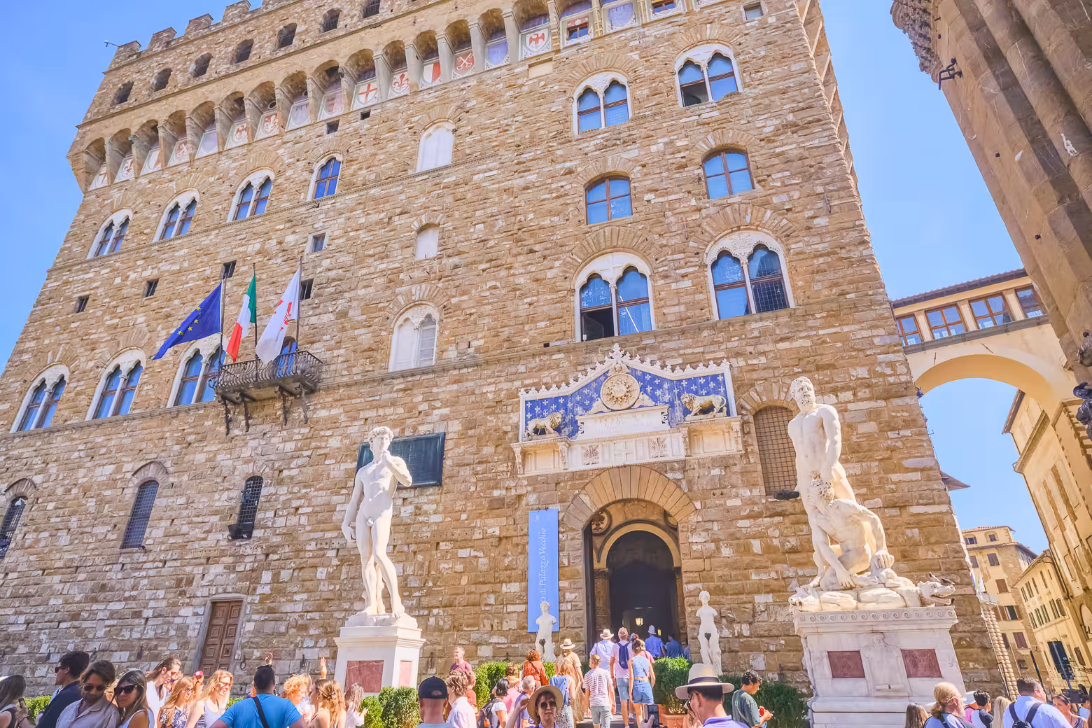 Visitors gather outside Florence's Palazzo Vecchio, admiring statues during best walking tour.