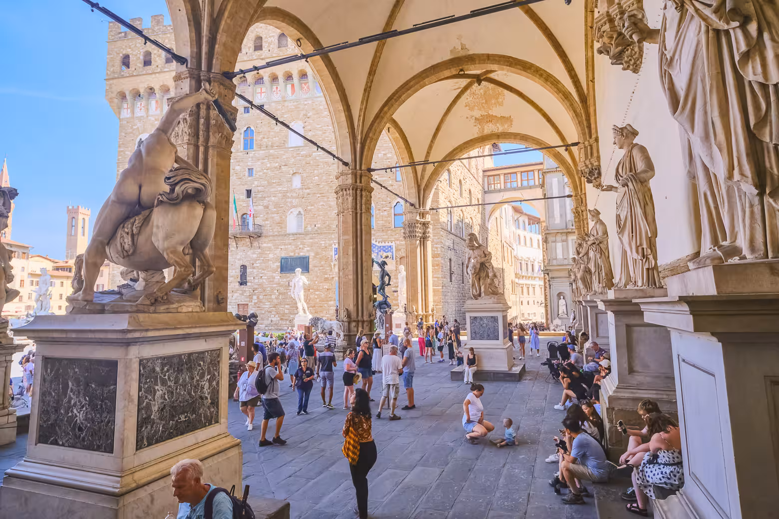 People enjoying the historic sculptures and architecture in Piazza della Signoria, Florence, on a monolingual group tour.