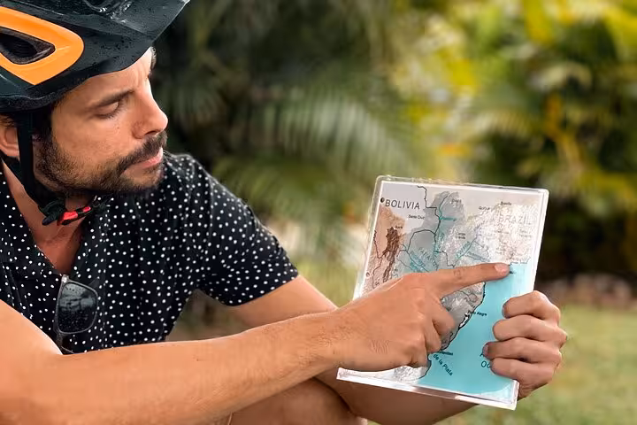 Tour guide explaining a map of Brazil during a Florianopolis bike tour, highlighting historical and cultural insights.