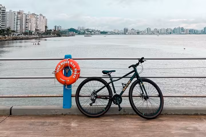 Bicycle parked on a Florianopolis pier with city skyline, perfect for bike tour exploring and street photography.