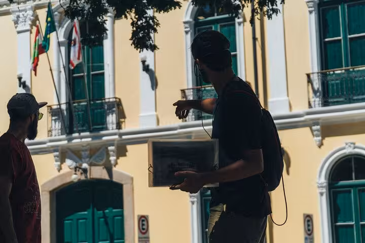 Tour guide pointing at historic architecture on Florianopolis walking tour, emphasizing cultural and historical insights.