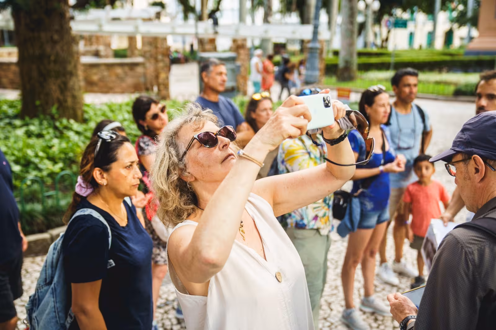 Tourists capturing moments on a Florianopolis walking tour amidst lush greenery and historic sites.