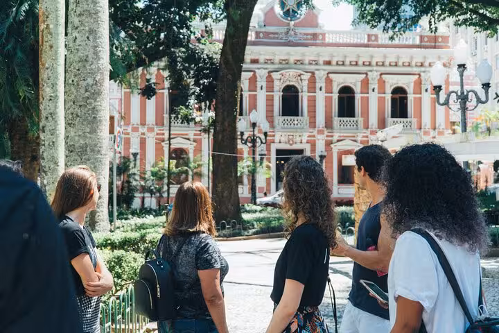 Visitors admire historical architecture surrounded by greenery on Florianopolis Walking Tour.