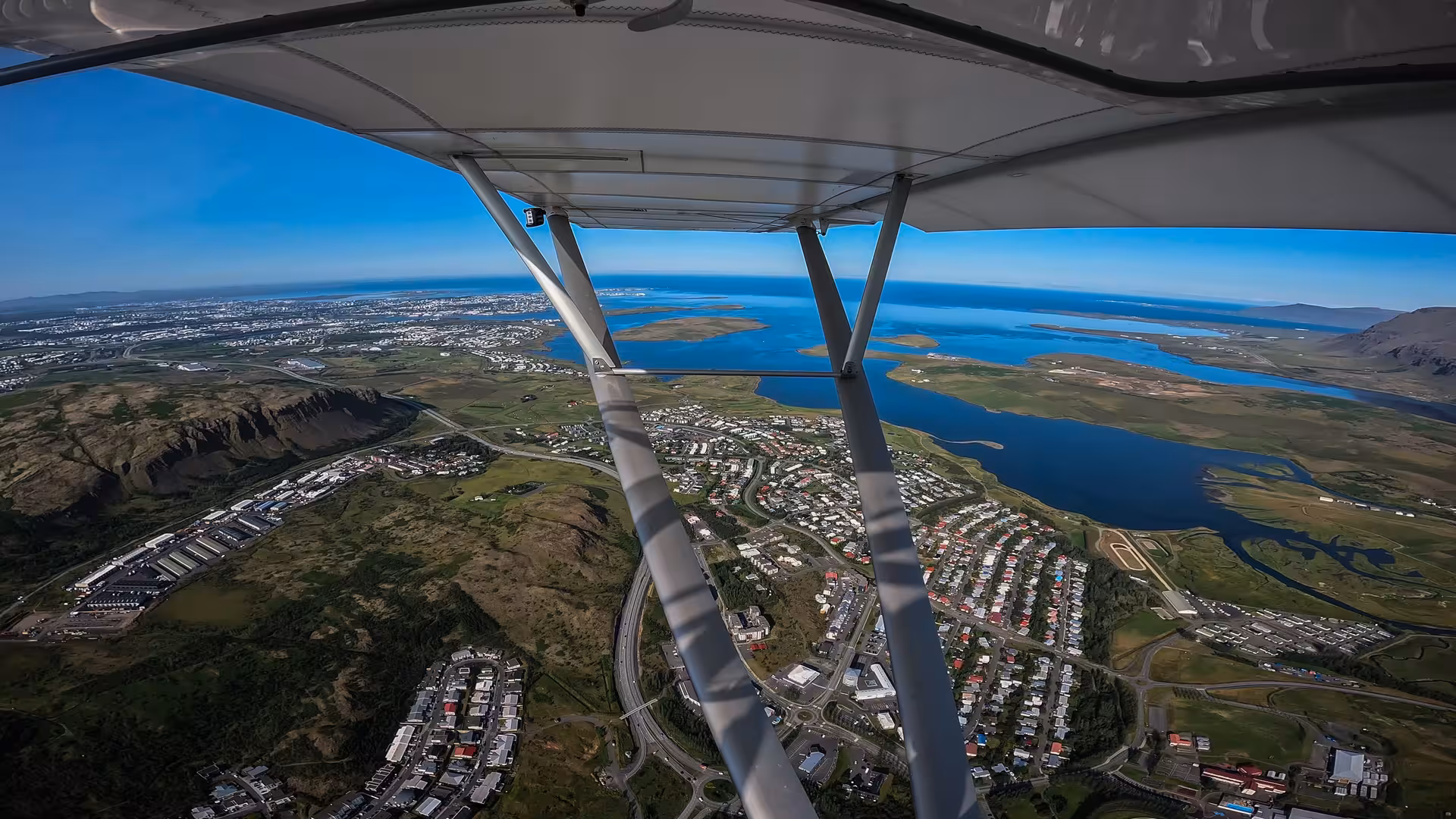 Aerial view from Flying Buggy plane over coastal city, islands and blue ocean on a scenic flight tour