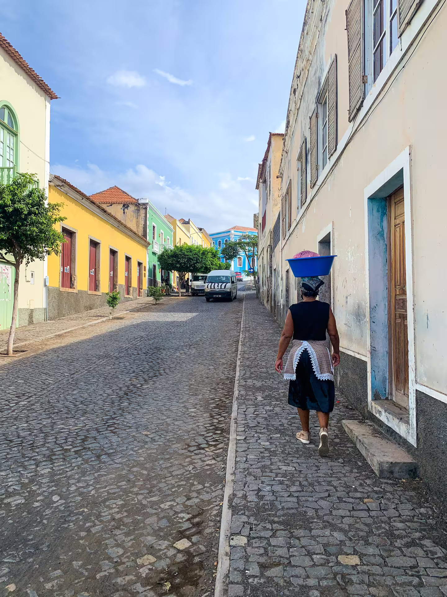 Local walking down a colorful cobblestone street in Fogo Island, part of Praia's full-day private experience.