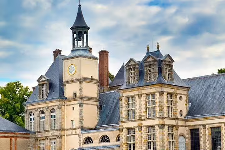 Clock tower and rooftops of Château de Fontainebleau, highlight of a Paris to Fontainebleau half-day tour