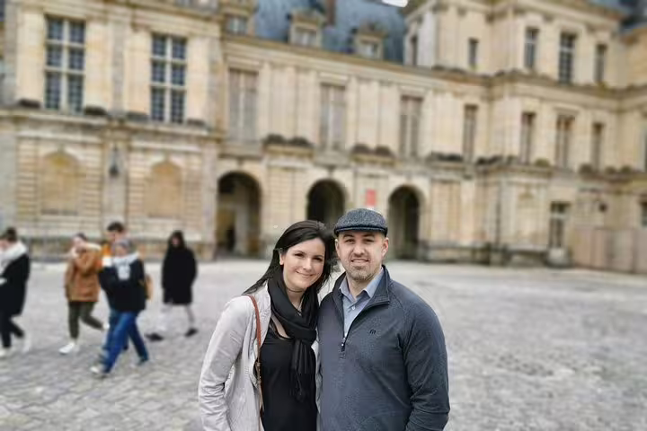 Visitors posing in Fontainebleau Castle courtyard, guided half-day tour from Paris to Château de Fontainebleau
