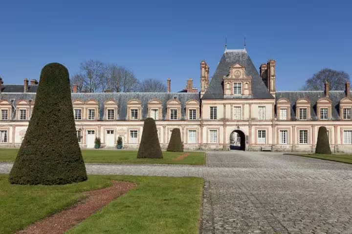 Fontainebleau Castle courtyard with clipped topiary and cobblestones on a half-day trip from Paris