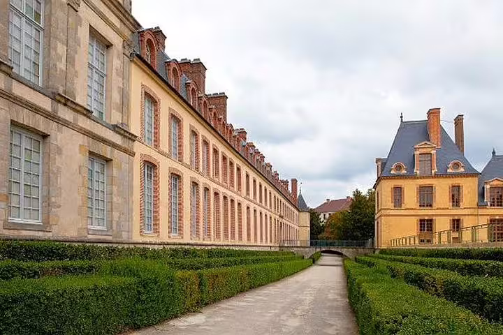 Garden walkway beside Fontainebleau Castle, a highlight of a half-day guided tour from Paris