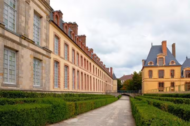 Garden path beside Fontainebleau Palace wings, a top stop on a half-day tour from Paris