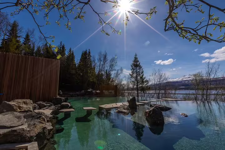 Forest Lagoon geothermal pool with turquoise water, natural rocks, lake and snow-capped mountains in Akureyri Iceland