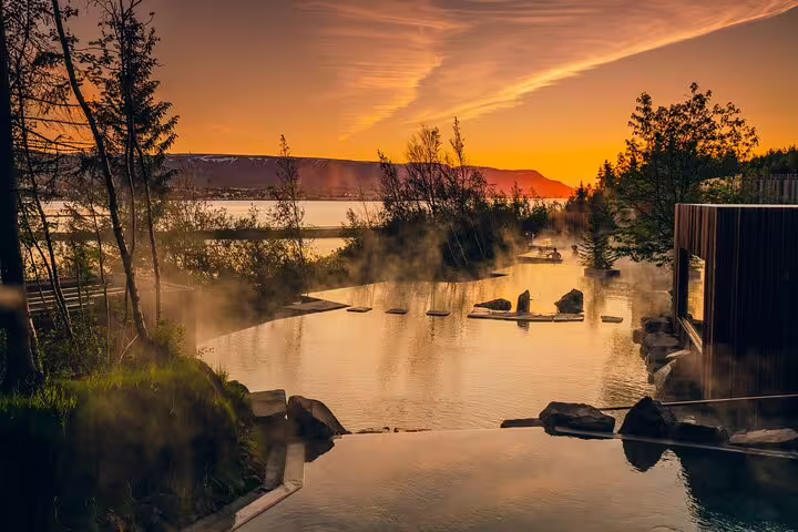 Steaming geothermal Forest Lagoon pool at sunset with golden sky and misty waters in Iceland