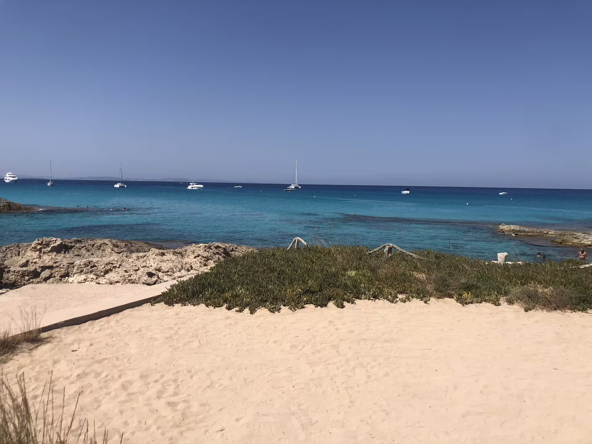 Formentera cove with yachts on blue water, visited on Ibiza day trip with transfers and fast ferry included