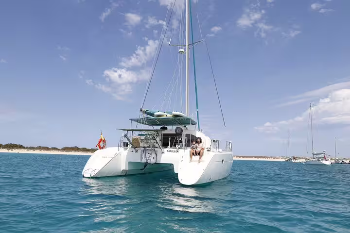 Catamaran sailing near Formentera's pristine beaches on a sunny day, perfect for an Ibiza small group adventure tour.