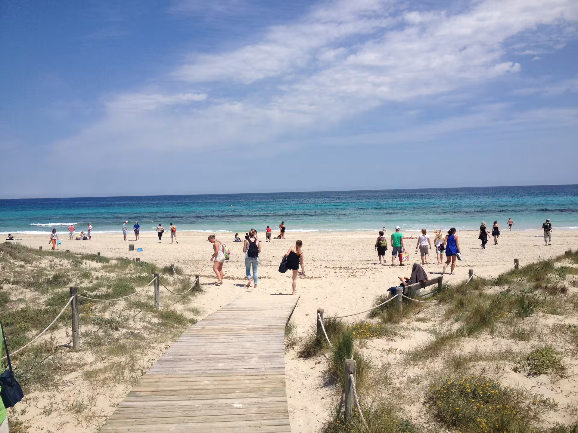 Wooden boardwalk to a turquoise Ibiza beach, a scenic stop on the Ibiza bus tour with fast ferry and guide