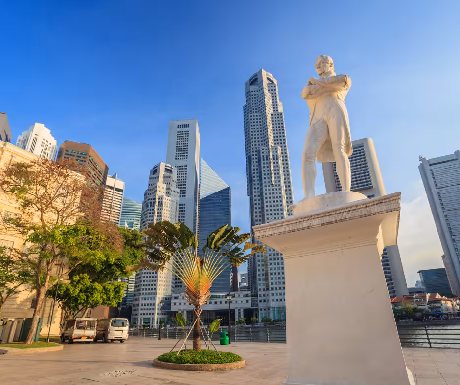 Statue in Civic District with modern skyscrapers and lush greenery under a clear blue sky in Singapore.
