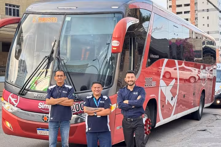 Fortaleza Airport to Orla Marítima hotel transfer team standing by modern red coach for safe shared ride