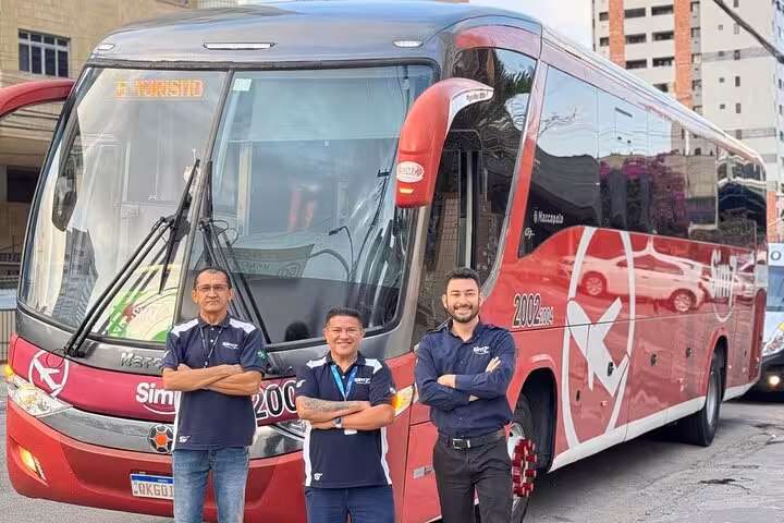 Friendly staff beside executive coach for Fortaleza Airport transfer to Orla Marítima hotels and resorts, Ceará