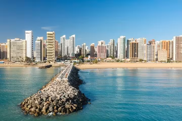 Rock jetty and calm sea at Fortaleza Orla Marítima with high-rise hotels, from Fortaleza Airport transfer route