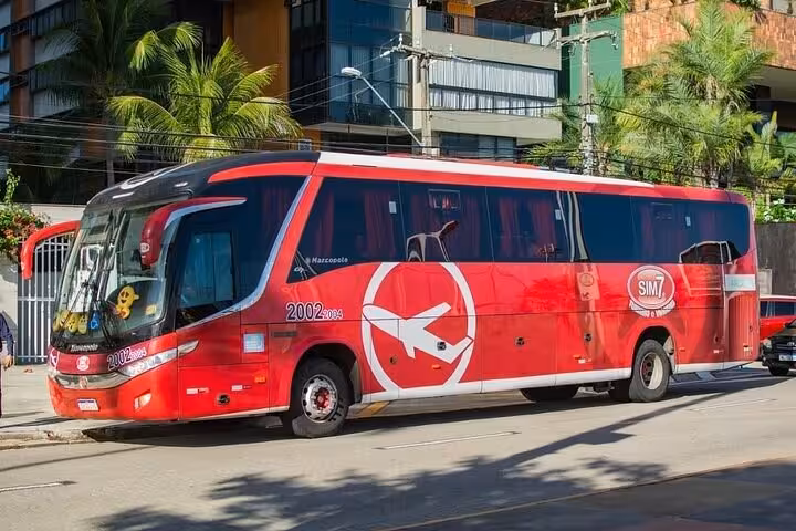 Red coach shuttle on city street for Fortaleza Airport transfer service to Orla Marítima beachfront hotels